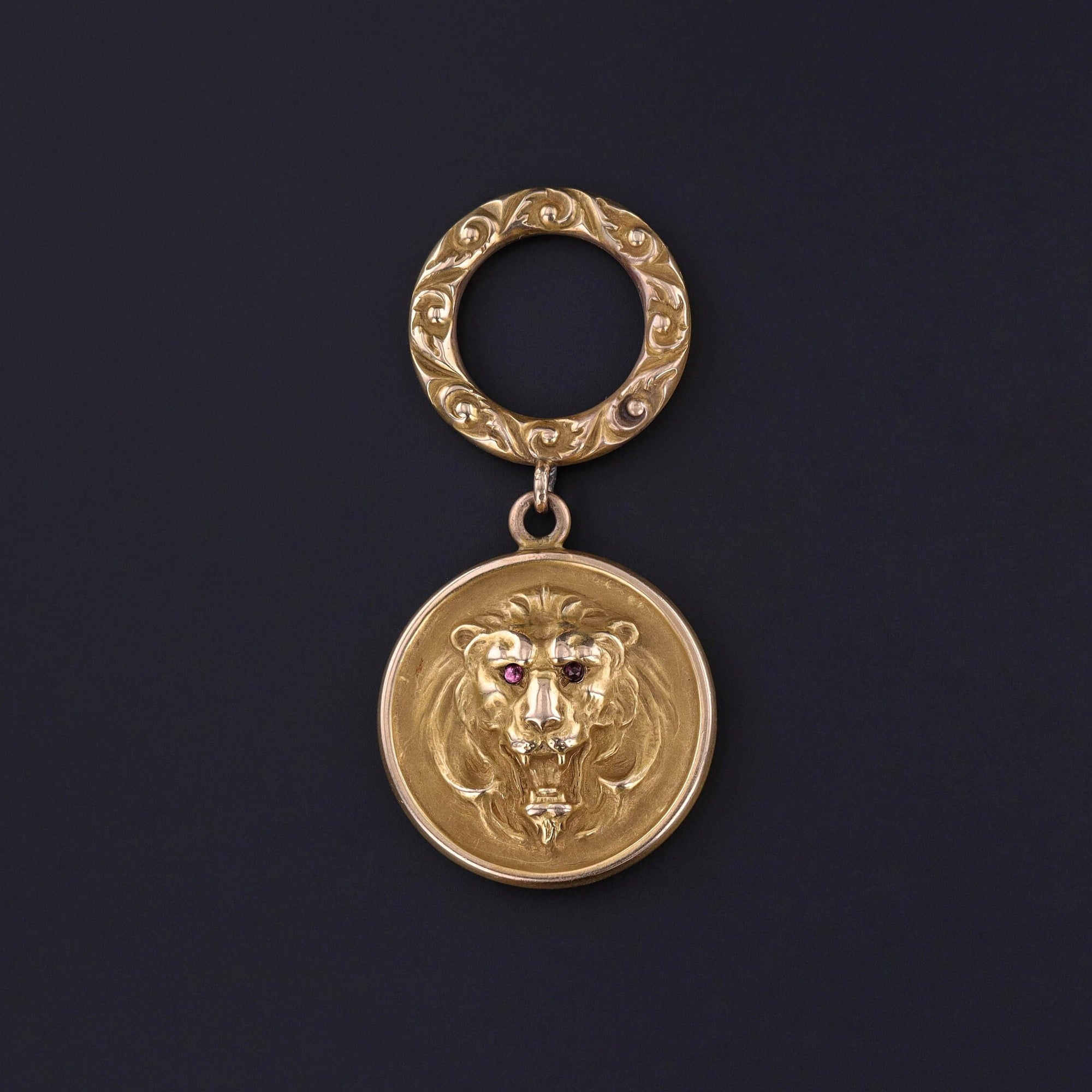 Antique Gold Lion Pendant: Discover the regal elegance of this antique 10k gold pendant (circa 1890-1900) boasting a majestic lion motif hanging from an embossed bolt ring. The reverse is inscribed with the initials &#39;VRH&#39;.