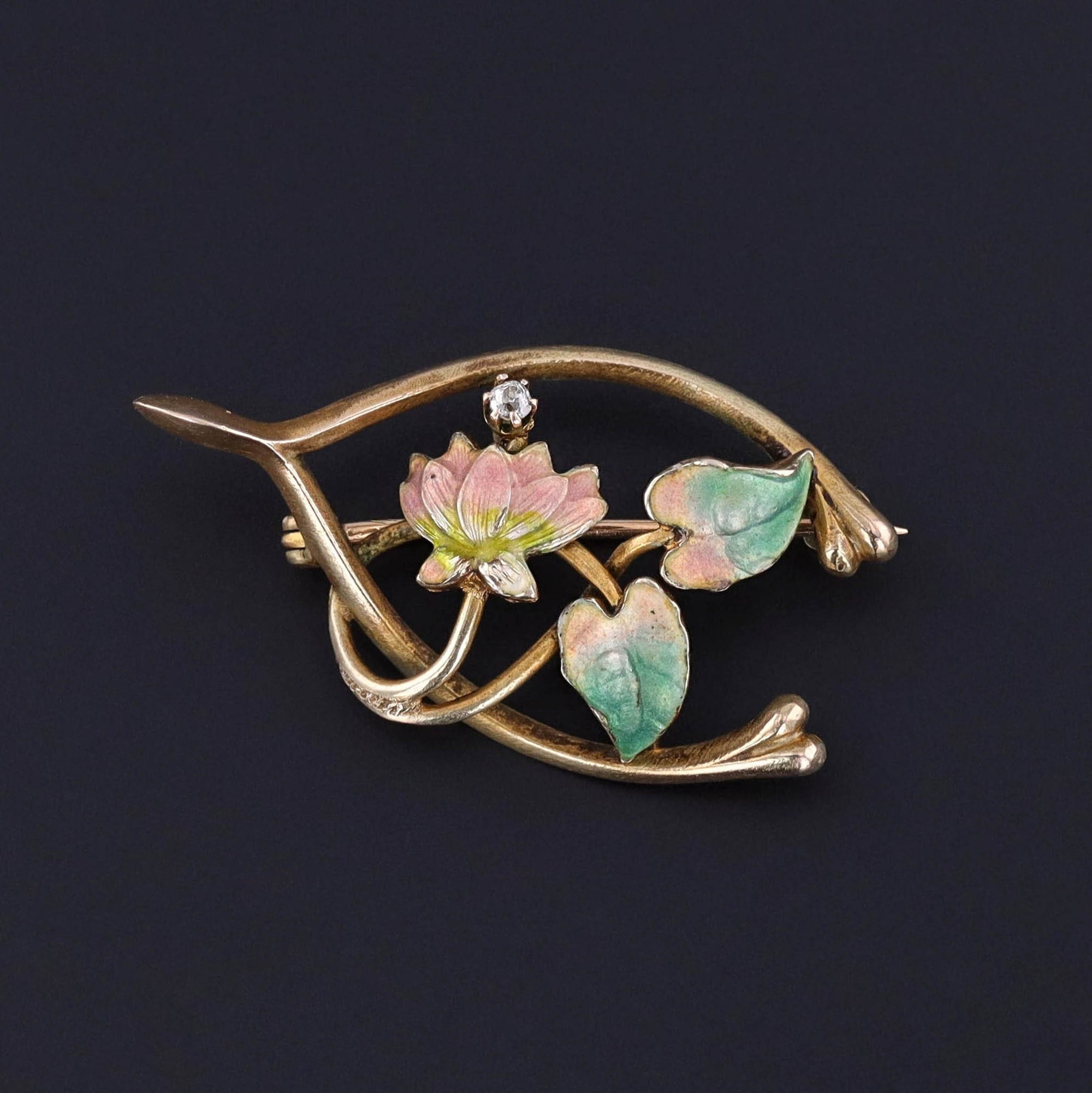An antique 14k gold enamel and diamond wishbone brooch adorned with a lily flower. The brooch dates to the early 1900s (circa 1910) and is in great condition.