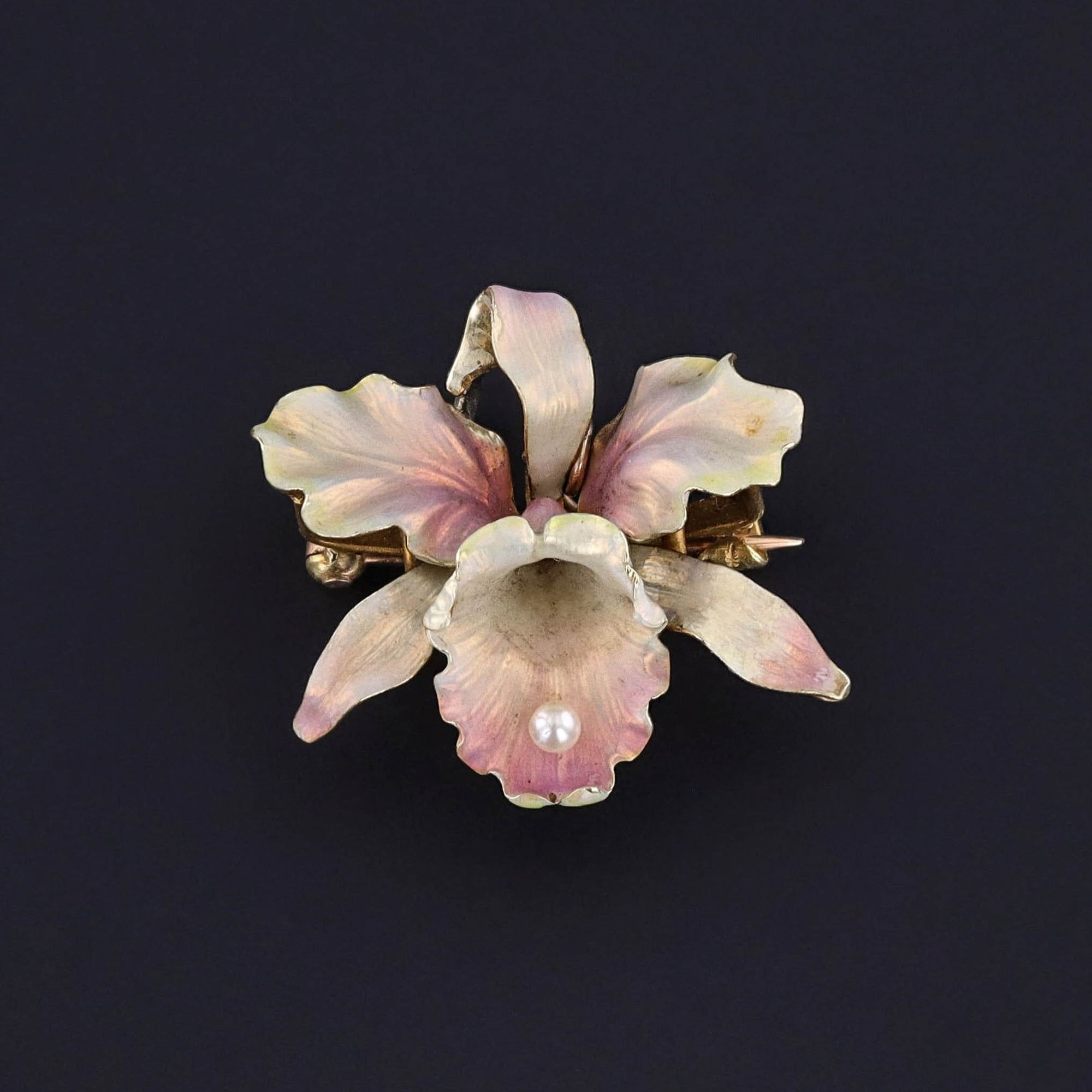 Transport yourself back to the elegant Art Nouveau era with this antique jewel showcasing a 14k gold orchid adorned in iridescent pink enamel. The pin findings bear the makers mark for the renowned Whiteside & Blank of Newark, NJ.