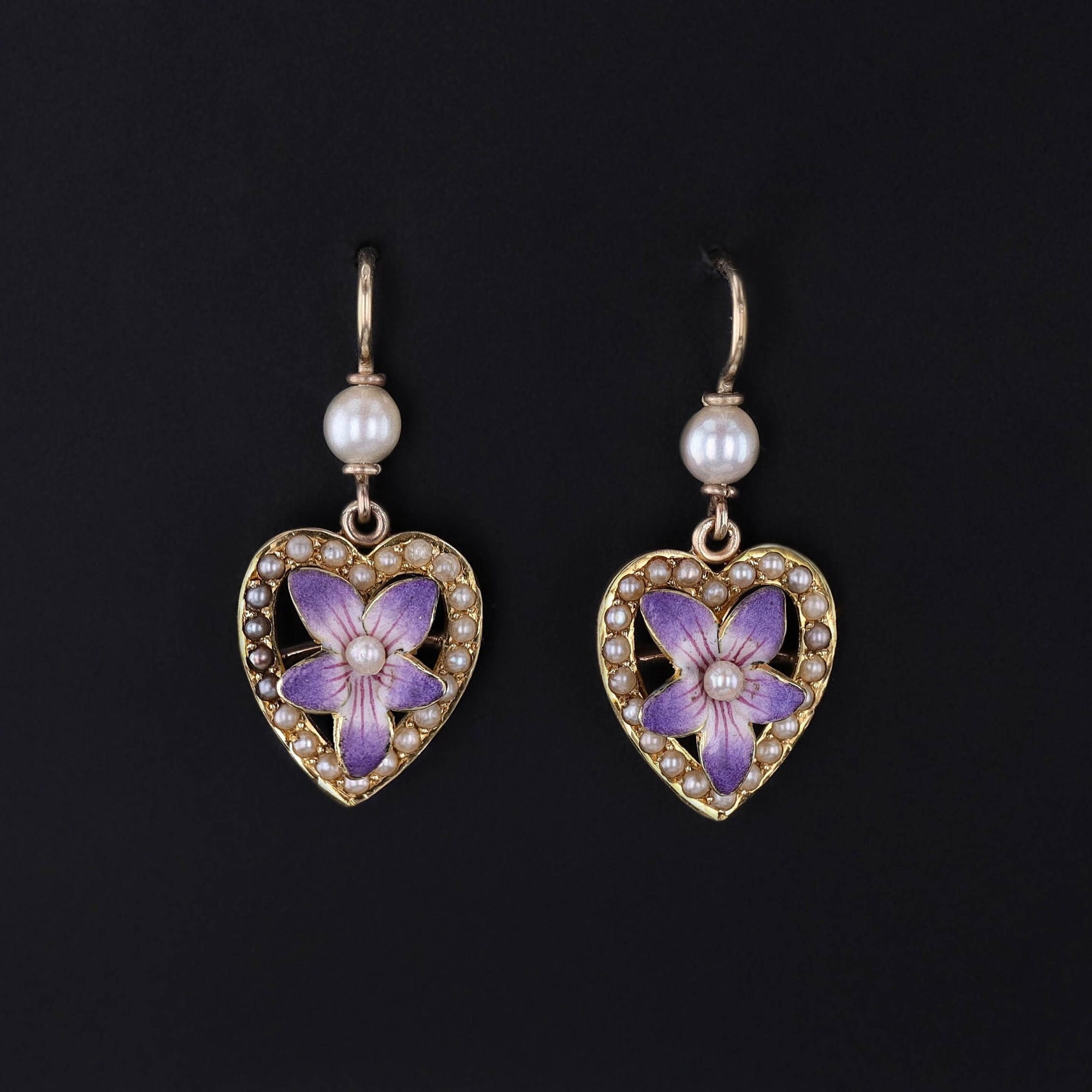 Antique Violet flower earrings created from an antique pin from the early 1900s. The earrings are 14k gold and feature purple enamel violets adorned with pearls set inside of hearts.
