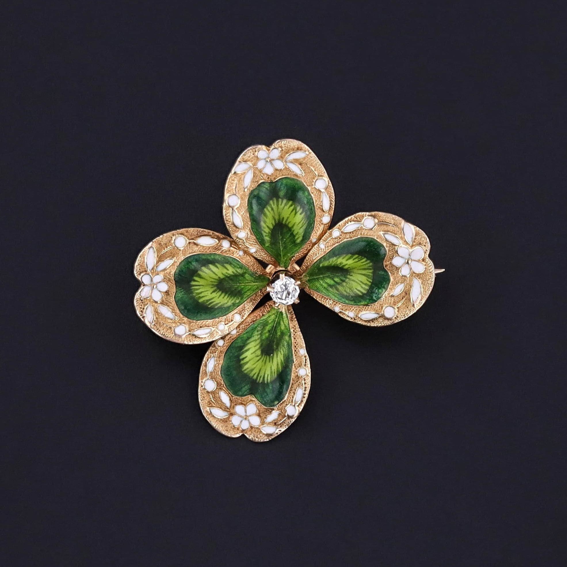 An antique enamel clover brooch by Krementz and Company dating to the early 1900s. The brooch is in excellent condition with green and white enamel and a glittery diamond accent. It is 14k gold and great for any jewelry collector.