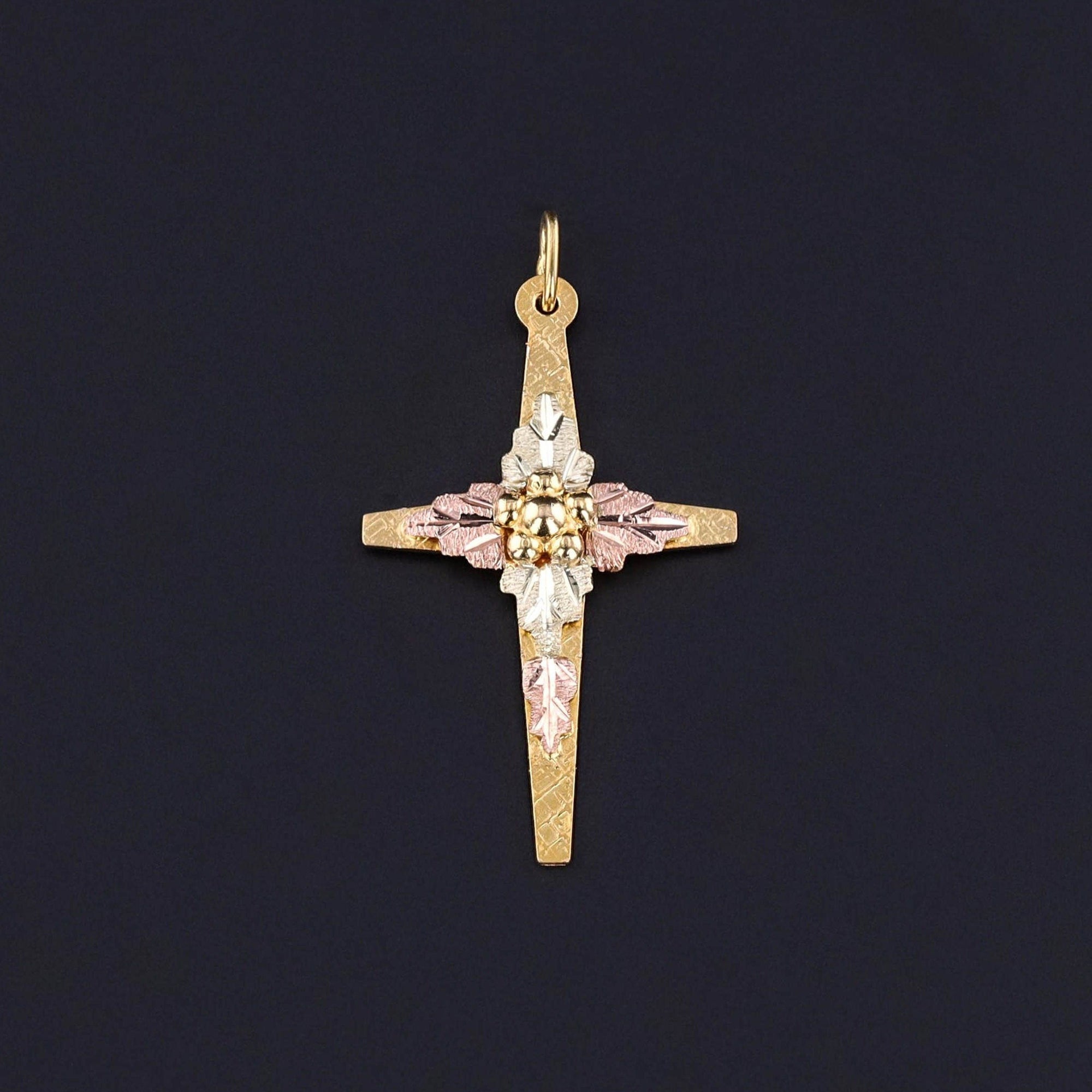 Vintage Gold Cross Pendant: This 1980s piece is perfect for anyone of Christian faith. The pendant features a yellow gold cross adorned with delicate flowers and leaves crafted from rose and green gold.