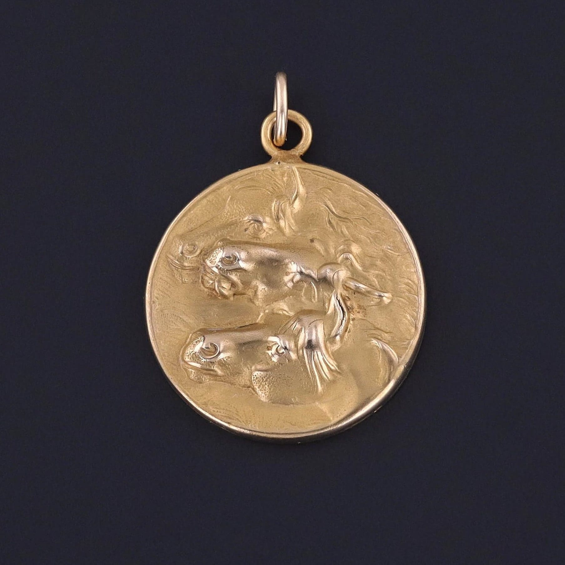 An antique pendant featuring three horse heads.