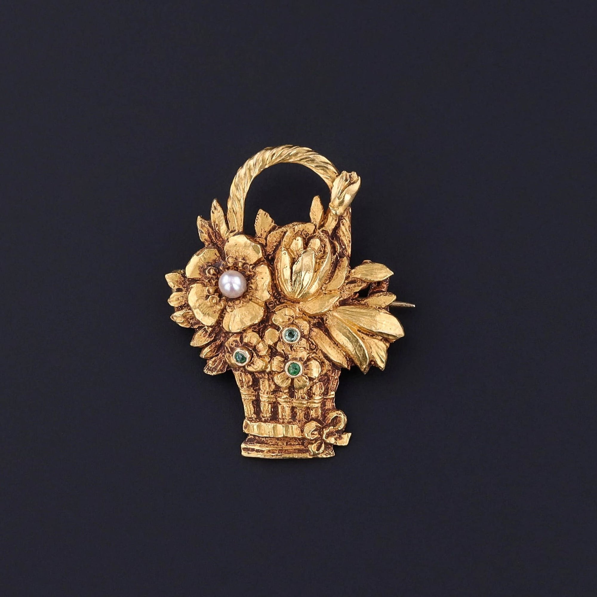 A Vintage Flower Basket Brooch: A finely rendered brooch of 14k gold showcasing a basket of blooms adorned with emeralds and a pearl accent. The brooch is in great condition and would be perfect for any jewelry collector.