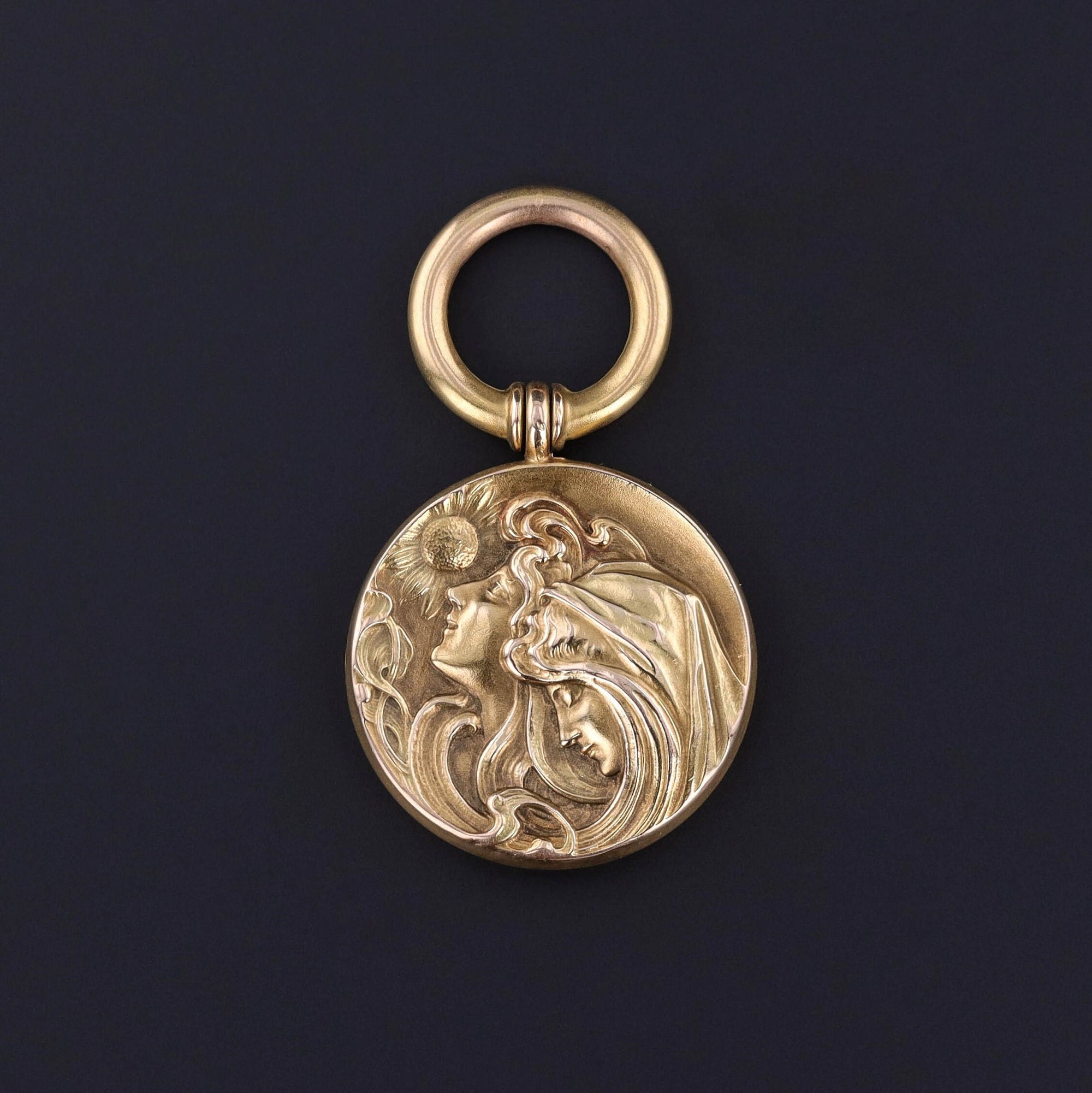 Art Nouveau pendant displaying two women and a sunflower. The women could be sisters, a mother and daughter, or two friends. It is 10k gold and in great condition.