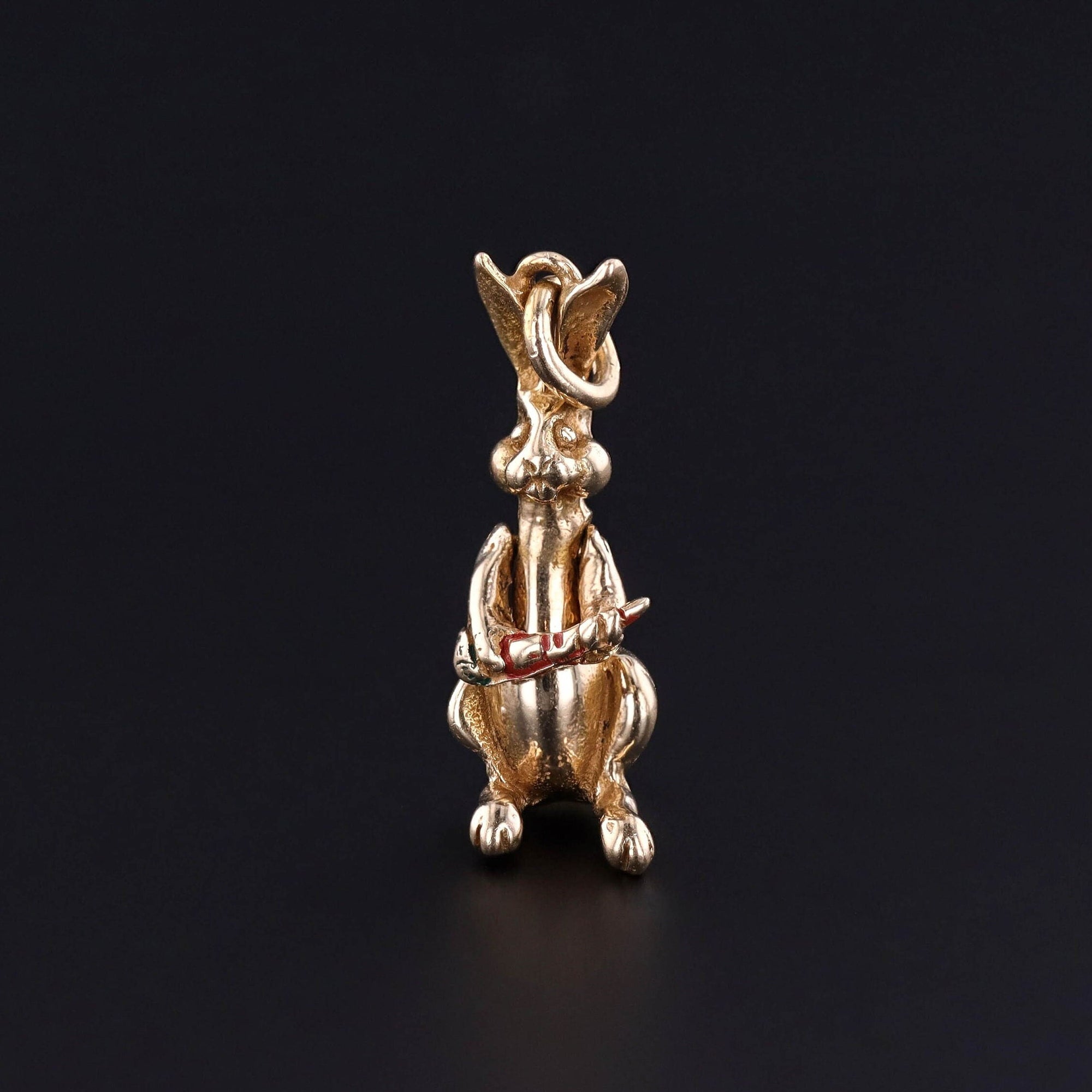 A solid gold moveable bunny rabbit charm. The rabbit holds a carrot in its arms and the arms raise to bring the carrot to its mouth. The piece dates to the 1950s- 1960s. It is in good condition with some wear to the enamel on the carrot.