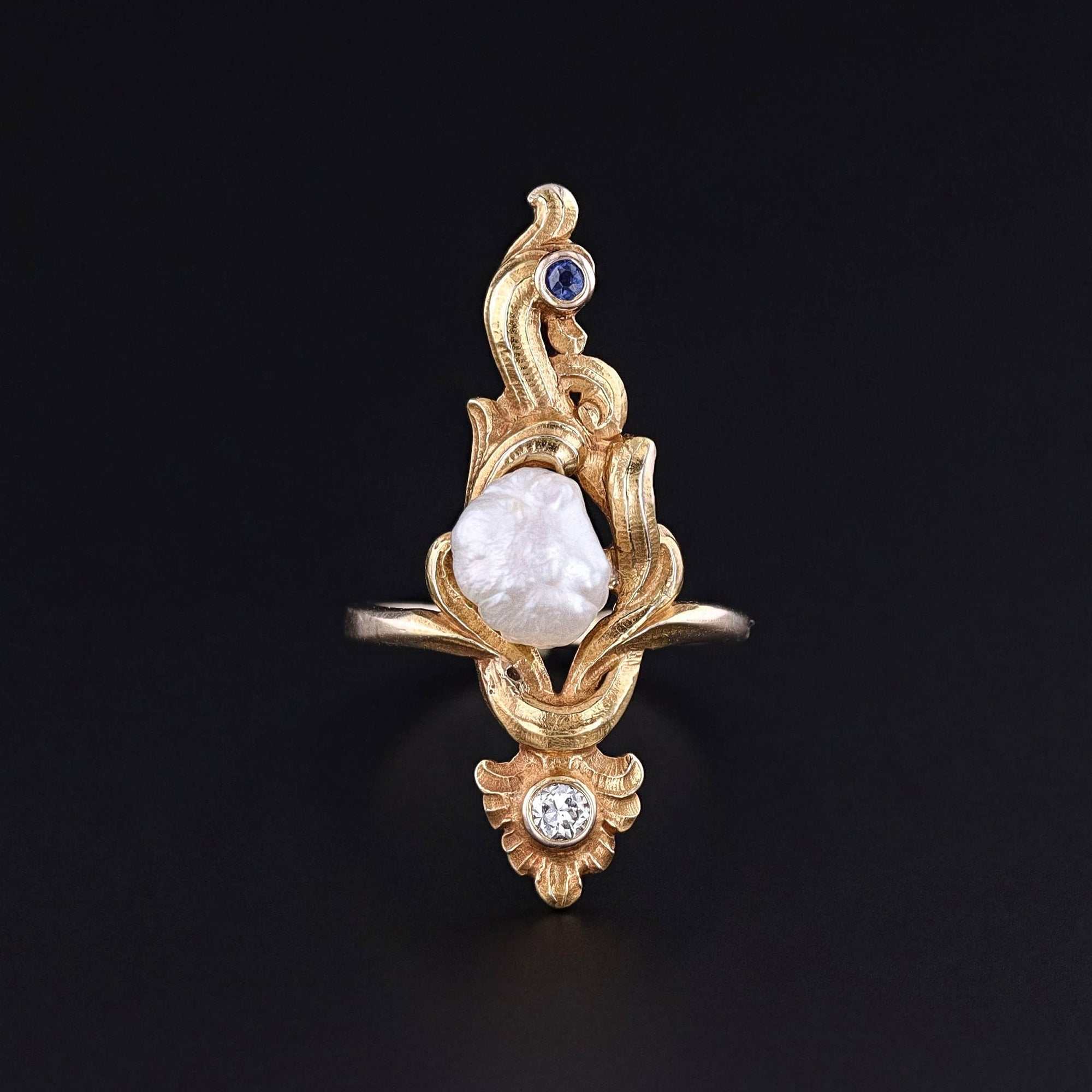 A baroque pearl, diamond, and sapphire ring from the Art Nouveau era. The ring is solid 14k gold and in excellent condition. It can be re-sized free of charge. Perfect for any antique jewelry collector or ring collector.
