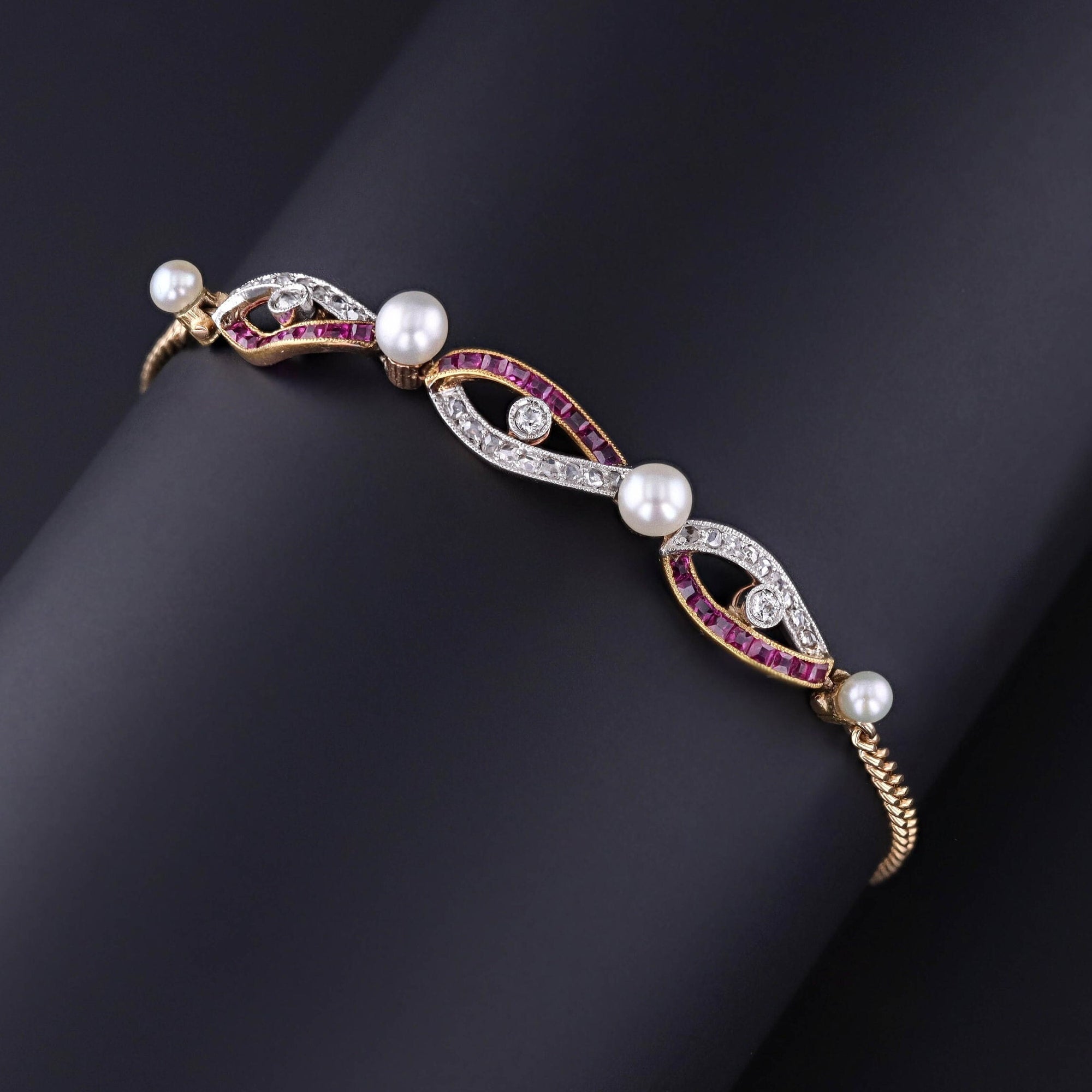 An Edwardian era bracelet with channel set natural rubies, rose cut diamonds, and four pearls. The bracelet dates to the early 1900s and is 14k gold with platinum accents near the diamonds. It is in great condition and measures 7 inches.