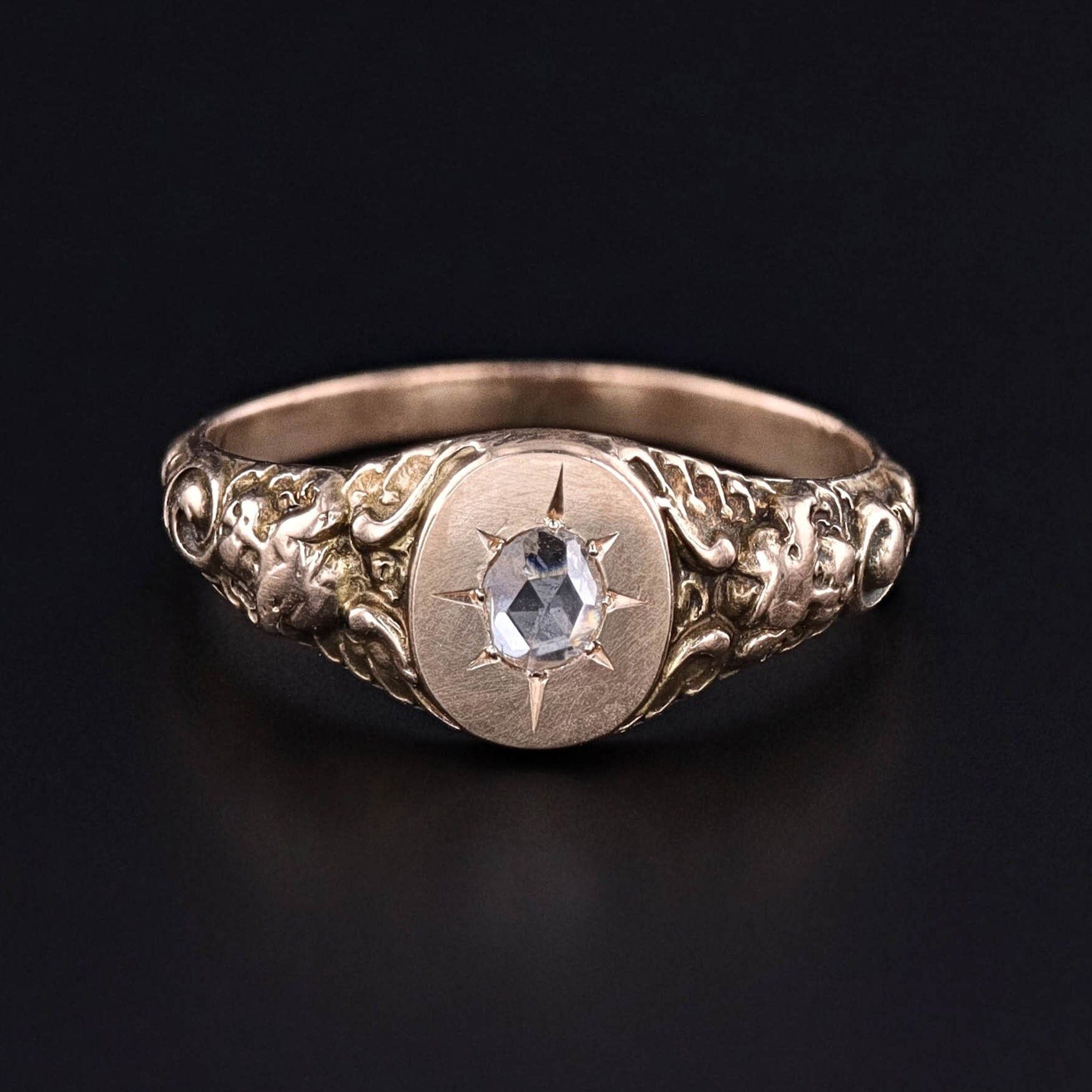An antique diamond cherub ring of 10k gold. The ring is gypsy set with a rose cut diamond in a hand engraved star pattern. Perfect for any cherub jewelry collector or antique jewelry lover.