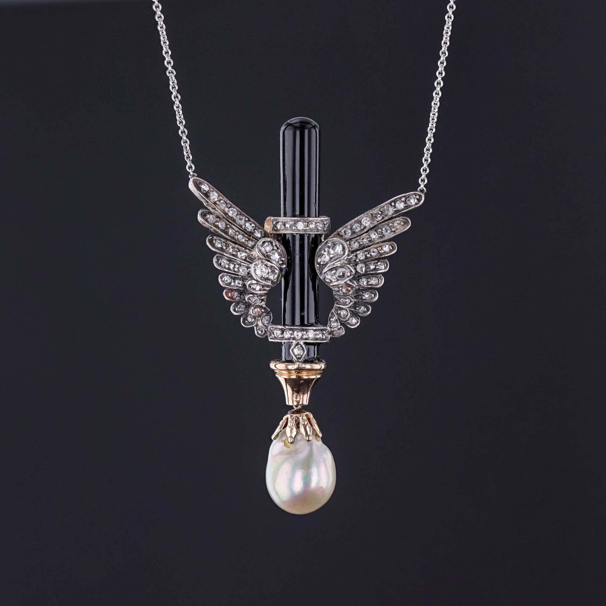 An antique diamond wing necklace with onyx and a lustrous baroque pearl set on a 14k white gold chain.