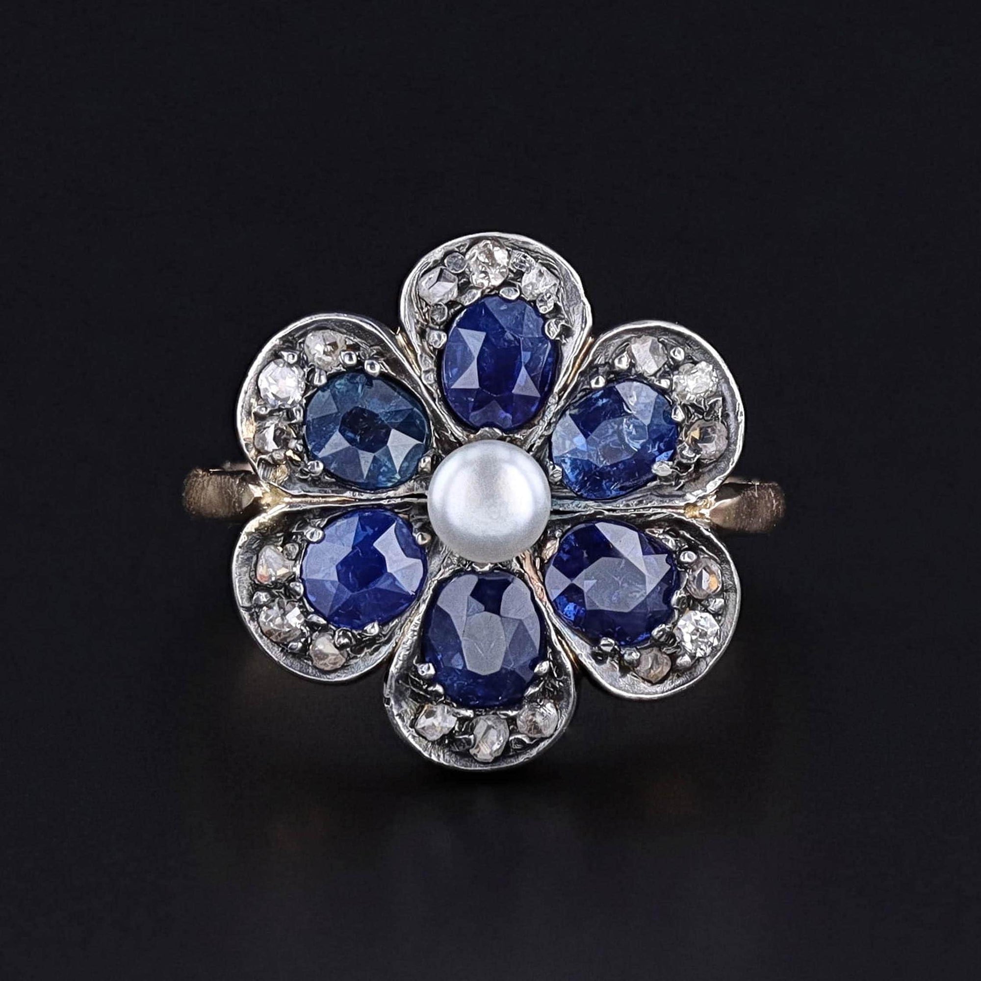 A vintage sapphire and diamond flower ring addorned with a button pearl.  The ring is silver topped gold and in great condition.