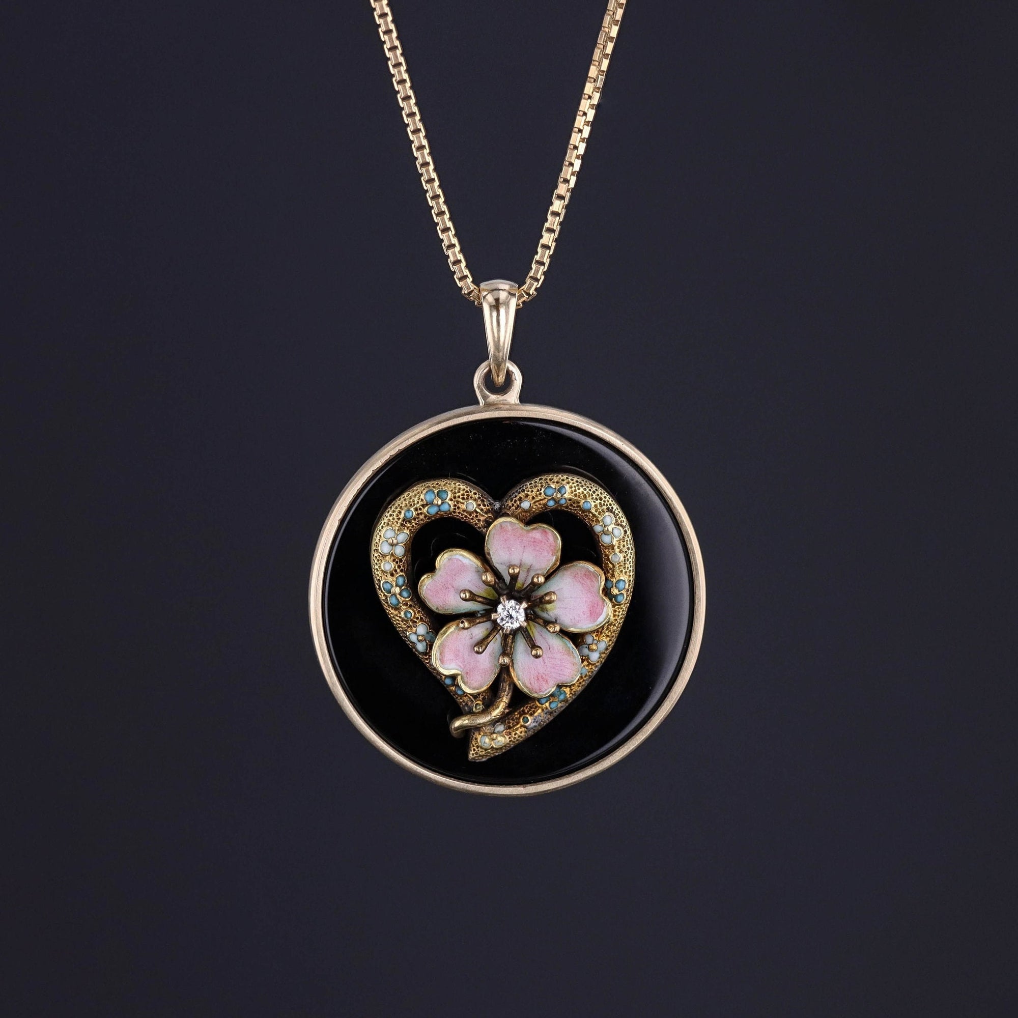 Pink enamel flower with a diamond on a gold heart with blue forget-me-not flowers on a black onyx with a gold chain.