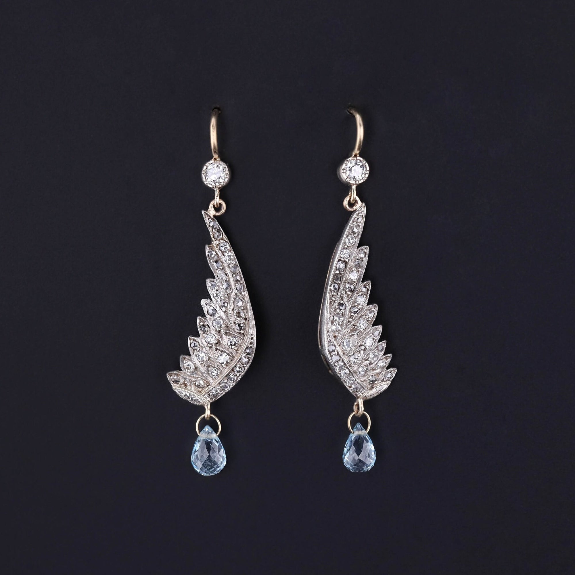 Dangle earrings featuring wings of 18k white gold and diamonds with blue topaz drops
