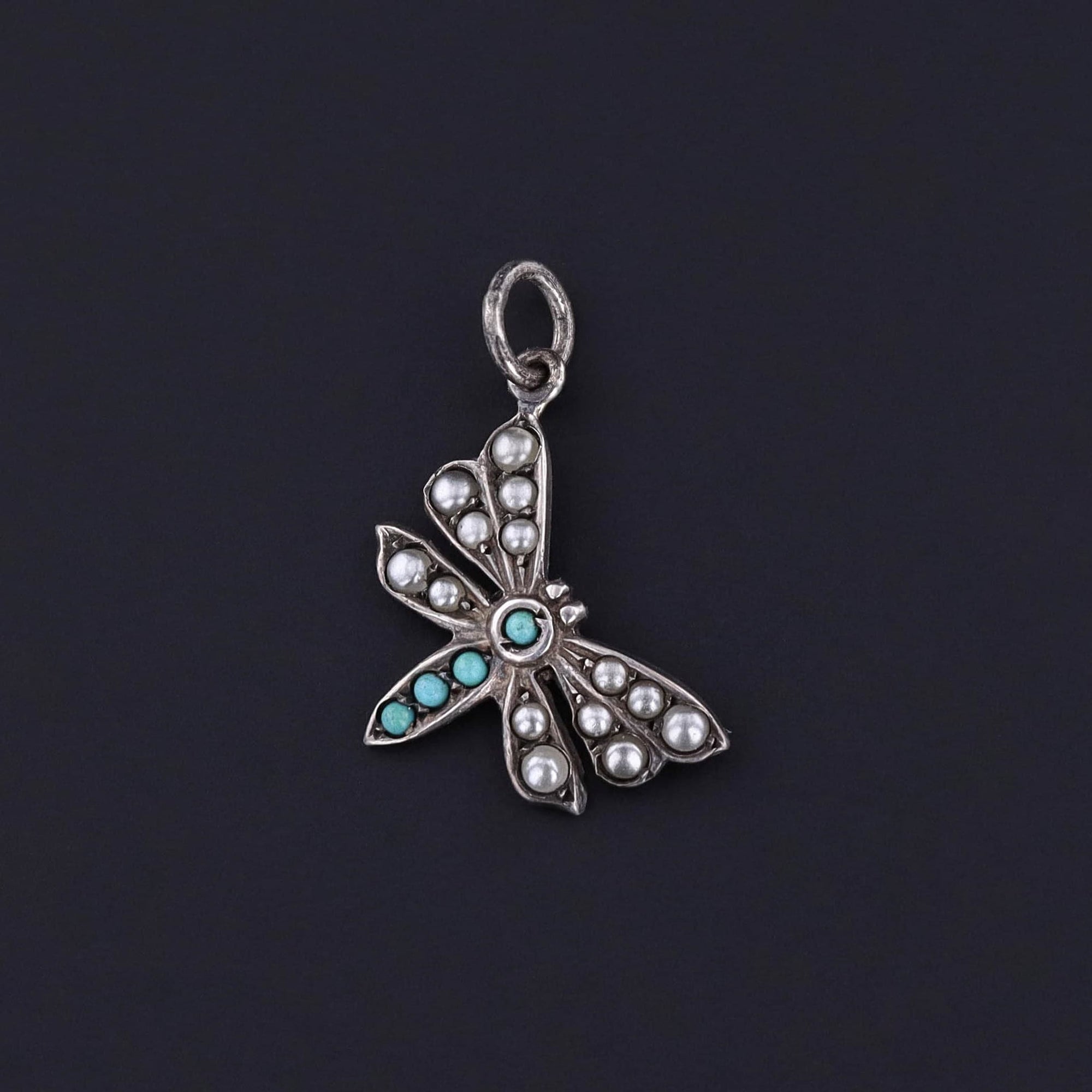 A vintage butterfly pendant adorned with simulated pearls and turquoise set in sterling silver. It was originally a 1970s pin.